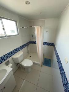 uma casa de banho com um WC, um chuveiro e um lavatório. em Casa de dos pisos a pasos de la playa em Bahia Inglesa