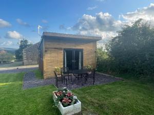 eine kleine Hütte mit einem Tisch und Stühlen im Hof in der Unterkunft Beautiful self-catering cottages, Ribble Valley in West Bradford