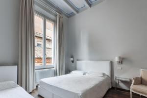 a white bedroom with two beds and a window at Opera Residence in Bologna
