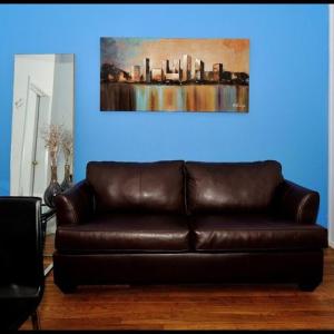 a brown leather couch in a living room with a painting at 4BR in the heart of Tribeca in New York