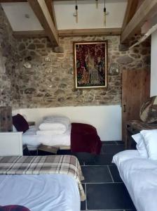The Stables in St Ives في سانت ايفيس: غرفة نوم مع ثلاثة أسرة في غرفة مسورة حجرية