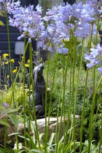 a statue of a bird sitting in the middle of purple flowers at The Stables in St Ives in St Ives