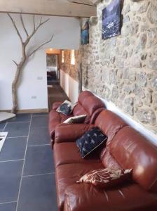 a brown leather couch in a room with a stone wall at The Stables in St Ives in St Ives