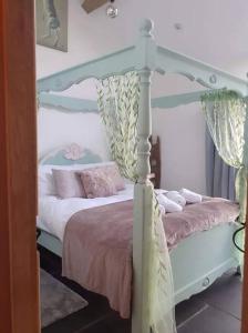 The Stables in St Ives في سانت ايفيس: غرفة نوم مع سرير المظلة البيضاء مع الوسائد