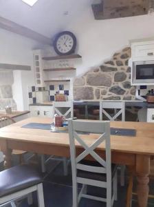 The Stables in St Ives في سانت ايفيس: مطبخ مع طاولة خشبية وساعة على الحائط