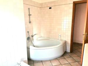 a white tub in a bathroom with a tiled wall at Villa Simone (Cagliari, Escalaplano, Sardegna) 