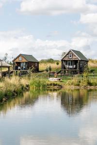 a couple of houses next to a river at Lake View Lodges in Long Melford