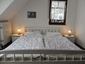 1 dormitorio con 1 cama blanca y 2 mesitas de noche en Ferienwohnung-Nils-Holgerson-mit-Balkon-zwischen-Strand-Wald-Wiese-im-Suedosten-der-Insel-Ruegen, en Gustow