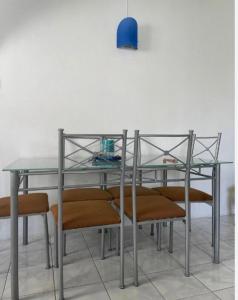 une table en verre avec des chaises et une lampe bleue dans l'établissement White appartment, à Flic-en-Flac