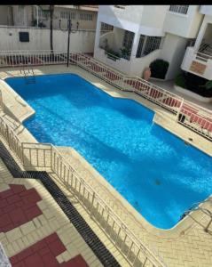 une grande piscine bleue au milieu d'un bâtiment dans l'établissement White appartment, à Flic-en-Flac