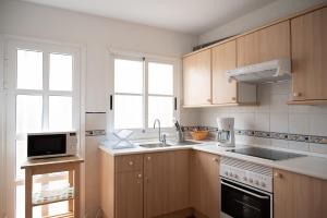 a kitchen with wooden cabinets and a sink and a microwave at VILLA ADELA in Callao Salvaje