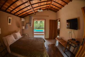 1 dormitorio con 1 cama, TV y ventana en Chalés da Estrada Velha, en Tiradentes