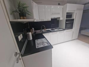 a kitchen with white cabinets and a black counter top at Apartman Samantha in Vinkovci