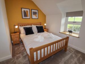 a bedroom with a bed with white sheets and a window at Rhos Las in Derwen