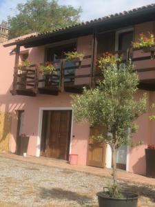 ein rosa Haus mit einem Baum davor in der Unterkunft Antico Borgo di Liteggio in Cologno al Serio