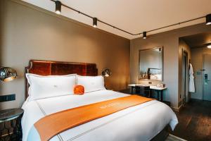 a bedroom with a large white bed with an orange pillow at Soho Grand Hotel in New York