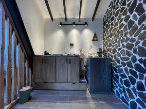 a kitchen with wooden cabinets and a stone wall at Ecoluxury Glamping in San Antonio de Pereira
