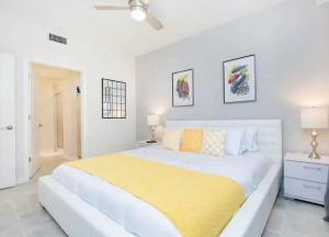 a white bedroom with a large bed with a yellow blanket at A Luxurious Getaway Key Location in Orlando