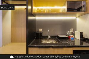 a kitchen with a sink and a microwave at Charlie Girassol Vila Madalena in Sao Paulo