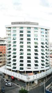 - un grand bâtiment blanc avec un panneau dans l'établissement San Diego Governador Valadares, à Governador Valadares