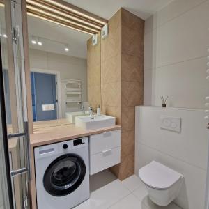 a bathroom with a washing machine and a sink at Baltea Sunrise Apartment - blisko Parku Reagana i plaży in Gdańsk