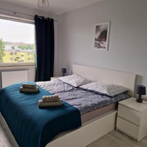 a bedroom with a bed with two towels on it at Baltea Sunrise Apartment - blisko Parku Reagana i plaży in Gdańsk