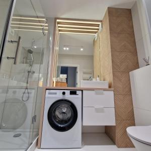 a bathroom with a washing machine and a shower at Baltea Sunrise Apartment - blisko Parku Reagana i plaży in Gdańsk