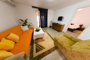uma sala de estar com um sofá laranja e uma cadeira em Apartman Bucko em Bihać