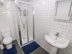a bathroom with a toilet and a sink and a shower at Cwtch Ar Y Mor in Burry Port