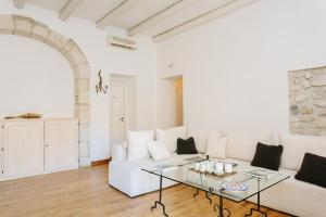 a living room with a white couch and a glass table at B&B Palazzo Del Sale in Syracuse