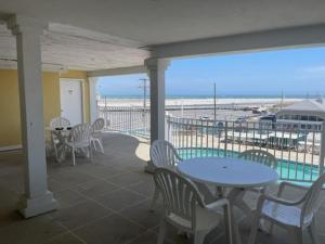 a patio with tables and chairs and a view of the beach at Nw Condo Steps To Beach Overlooking Pool & Ocean in North Wildwood