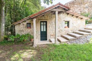 un pequeño edificio de piedra con una puerta y escaleras en Entre Os Ríos - Casa Rural y Enoturismo, en Pobra do Caramiñal