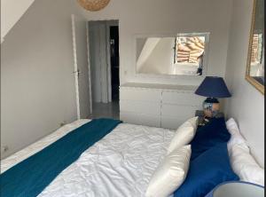1 dormitorio con cama, lámpara y espejo en Picsine, Tennis résidence sévigné 300m mer, en Deauville