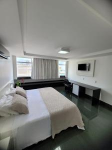 a bedroom with a white bed and a television at Garanhuns Palace Hotel in Garanhuns