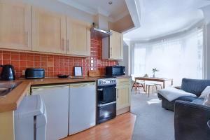 a kitchen with white appliances and a living room at Central Exeter's Perfect 2 BR Flat in Exeter