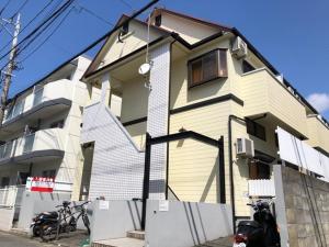 una casa amarilla y blanca junto a un edificio en The Mickey Carlton Ohashi Alpha Coat - Vacation STAY 15164 en Fukuoka