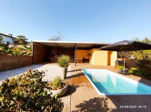 a house with a swimming pool and an umbrella at Casa com piscina e Quiosque! in Encantado