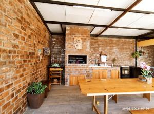 a room with a brick wall and a wooden table at Casa com piscina e Quiosque! in Encantado