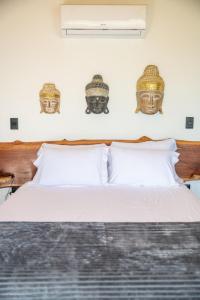 a bedroom with a bed with two masks on the wall at Pipa Sunset Villa in Pipa