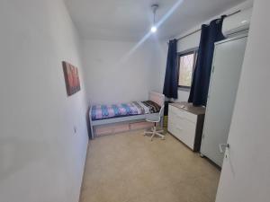 um pequeno quarto com uma cama e uma janela em בית על חצי דונם במרכז קרית שמונה em Quriate-Chemoná