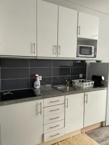 eine Küche mit weißen Schränken und einer Spüle und einer Mikrowelle in der Unterkunft Apartment São MARTINHO - Aveiro in Aveiro