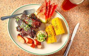 a plate of food with meat and corn on a table at Soho Grand Hotel in New York