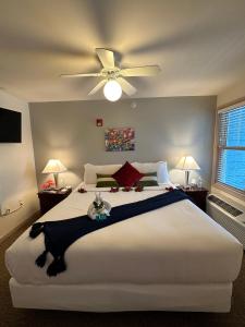 1 dormitorio con 1 cama blanca grande y ventilador de techo en Mill Creek Hotel, en Lake Geneva