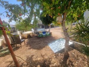 um quintal com cadeiras, uma mesa e uma árvore em בית על חצי דונם במרכז קרית שמונה em Quriate-Chemoná