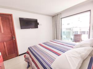 a bedroom with a bed and a flat screen tv at Hospedagem Stein - Suíte 402 in Domingos Martins