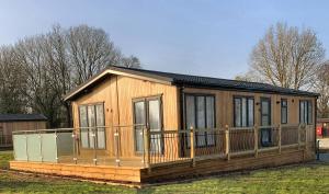 a large wooden house with a large deck at Shropshire Lodges - Romantic Luxury Hot Tub Breaks in Bridgnorth