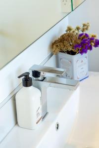 a bathroom sink with a soap dispenser and flowers at Modern Townhouse Cashel Street 2 bed 2 bath in Christchurch