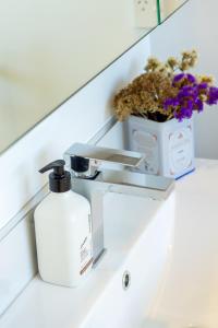a bathroom sink with a soap dispenser and flowers at Modern Townhouse Cashel Street 2 bed 2 bath in Christchurch +33 photos