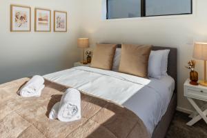 ein Schlafzimmer mit einem großen Bett mit Handtüchern darauf in der Unterkunft Modern Townhouse Cashel Street 2 bed 2 bath in Christchurch