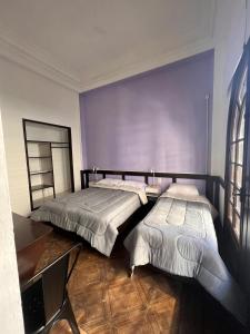 two beds in a room with purple walls at Nuevo Hotel Aramaya in Montevideo